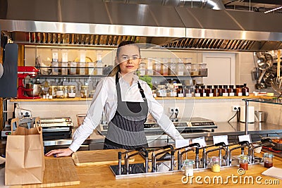 Portrait of young woman standing behind kitchen counter in small eatery Stock Photo